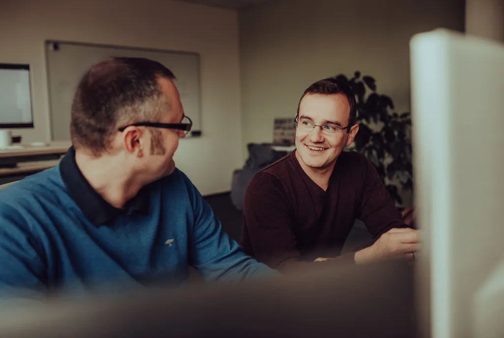 Zwei Personen sitzen an einem Schreibtisch